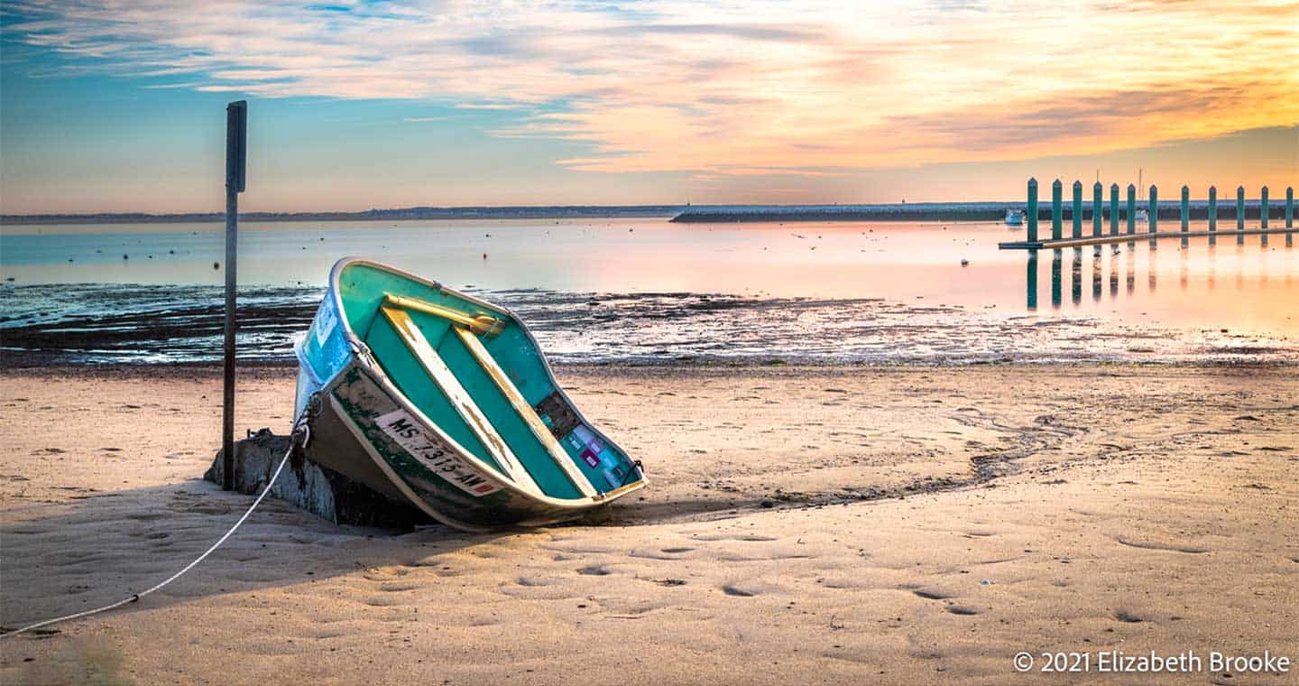  View of the beach as sunset with a green boat, Cape Cod, MA