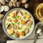 Clam chowder with croutons, with shells and a glass of white wine