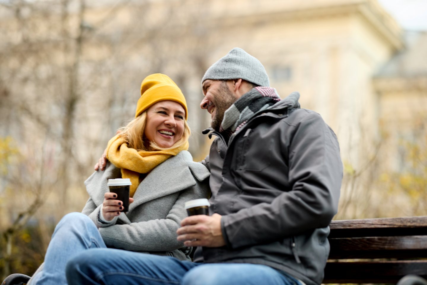 Couple drinking hot beverage sitting-on a park bench-in the winter in Provincetown