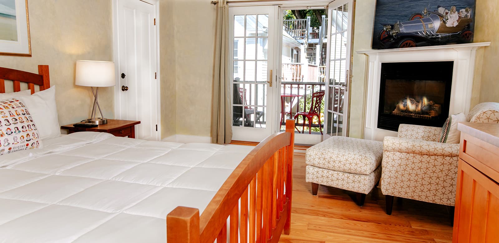 Queen size bed at our hotel room Mary Oliver with a glimpse of the fireplace and balcony