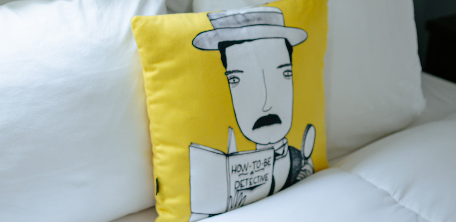 A throw pillow in the middle of the bed at Agatha Christie