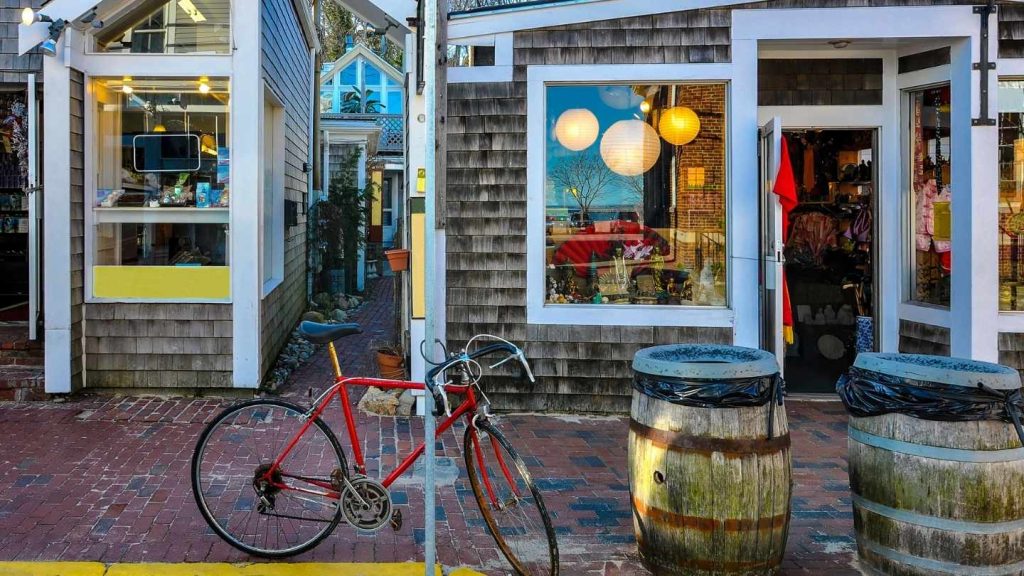 A bike leaning against a street sign in front of a Cape Cod Thrift Store