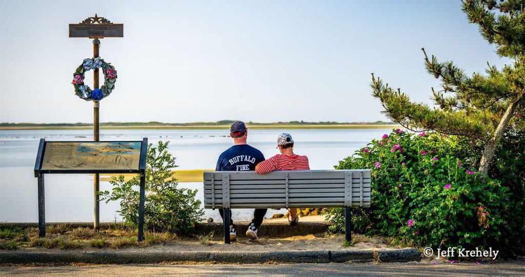 A couple sitting on a bench overlooking the water in Provincetown, MA