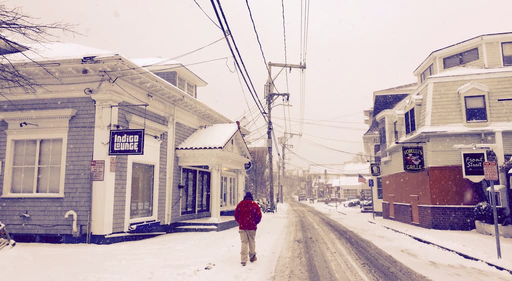 A man walking down Commercial Street as the snow falls around him during winter in Provincetown