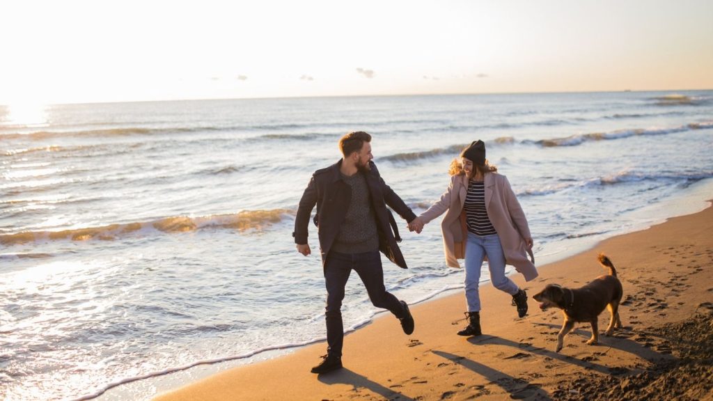 A couple walking along the shoreline with their dog during a romantic weekend getaway in Provincetown